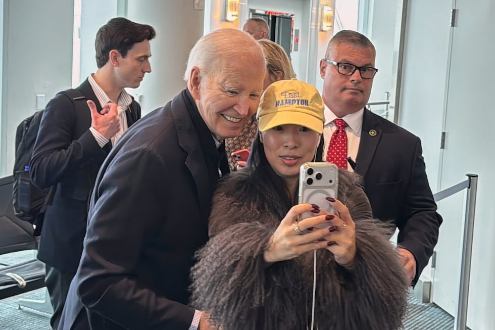 President Joe Biden is greeted by passengers awaiting an outgoing flight and poses for...