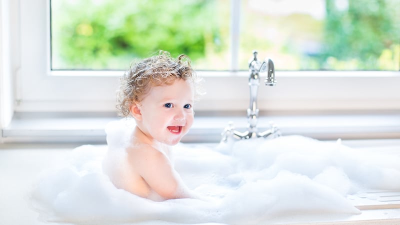 29702216 - happy laughing baby girl having fun playing with water and foam in a kitchen sink...